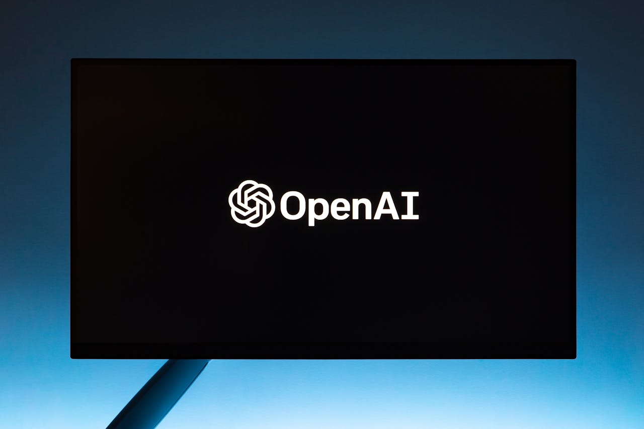 Minimalist display of OpenAI logo on a screen, set against a gradient blue background.